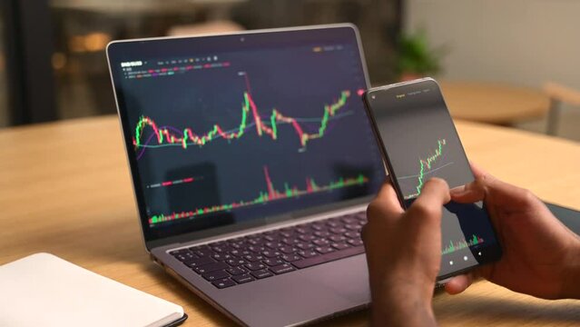 Crypto trader investor broker holding finger on the smartphone screen, using cell phone app, executing financial stock trade market trading order to buy or sell cryptocurrency