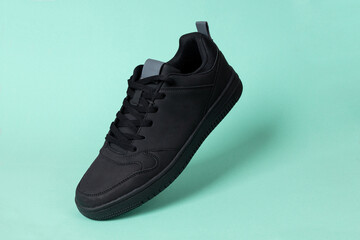 Black leather shoe on green background. Sport shoe, sneaker or trainer. Fitness, sport, training concept.