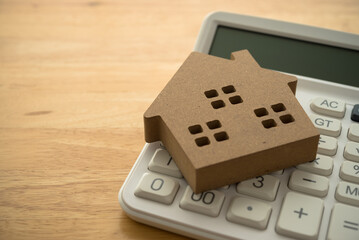 Wooden house on white calculator background copy space. Mortgage loan for buying home or real...