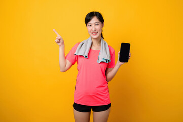 Portrait young asian sports fitness woman happy smile wearing pink sportswear and smartphone doing exercise training workout against yellow studio background. technology wellness lifestyle concept.