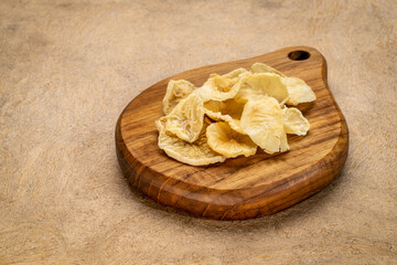 Dried slices of yacon tuber on a small wooden cutting board . Yacon contains inulin, a complex sugar, which promotes healthy probiotics. Superfood concept.