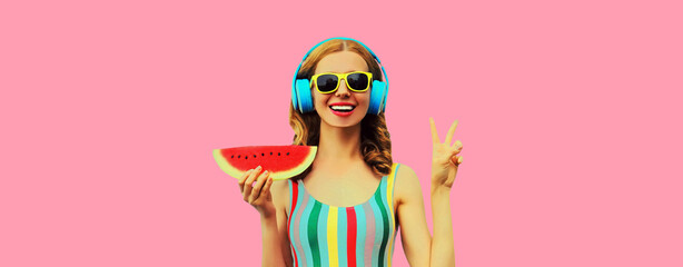Summer colorful portrait of cheerful happy laughing young woman 20s in headphones listening to music with juicy slice of watermelon on pink background