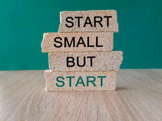 Start small but start symbol. Concept words 'Start small but start' on brick blocks on a beautiful green background. Business, motivational concept. Copy space.