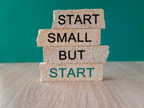 Start small but start symbol. Concept words 'Start small but start' on brick blocks on a beautiful green background. Business, motivational concept. Copy space.
