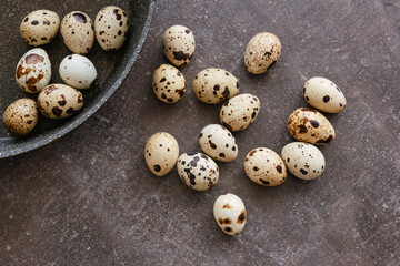 Quail eggs in a bowl on the dark stone table. Group of quail eggs. Top view