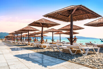 Emerald Black Sea and pebble beach and tourists, sunbeds and umbrellas, Aleksino, Krasnodar...