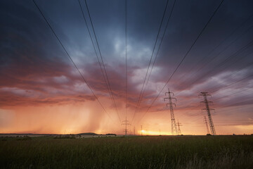 Landscape with electricity pylons under dramatic clouds of approaching rain with strong storm. Themes extreme weather, electrical energy and change climate..