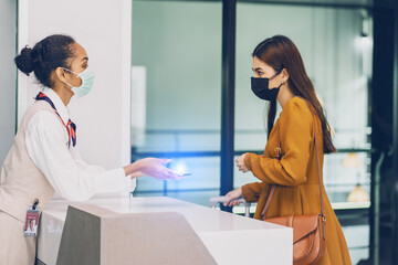 Fototapeta premium Airline stewardess working on the ground wearing face masks checking passports Asian female passengers departure-check-in issuing tickets with boarding pass counters airline at airport terminals 
