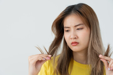 Asian woman very sad and upset looking at damaged hair, hair loss, hair thinning problem, vitamin...
