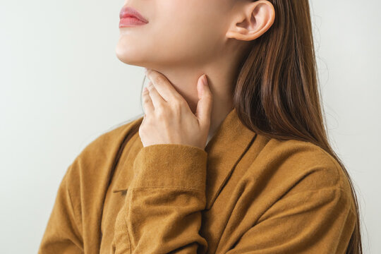 Sickness In Inflaming Asian Young Woman, Girl Use Hand Check Self Touch At Sore Throat, Pain Thyroid Gland On Neck Or Disease Reflux, Acid Of Suffer People On Wall Background. Medical And Healthcare.