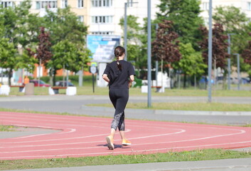 A female athlete runs on a treadmill at a street stadium, 
 Latvian Strelkov Street, Saint...