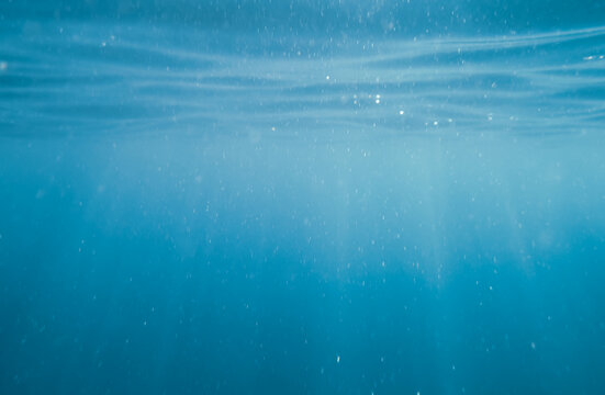 Burbujas bajo el agua de un azul profundo. Fotografía de la superficie del agua en el mar Adriático tomada desde abajo.