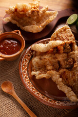 Chicharron. Crispy Fried pork rind, are pieces of aired and fried pork skin, traditional Mexican ingredient or snack served with lime juice and red hot sauce.