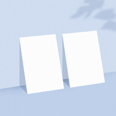 Two empty white paper sheets on light blue background with shadow overlay. The papers mock-up.