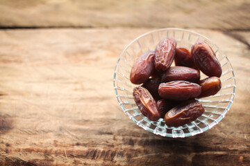 Bowl of pitted dates isolated on wooden background. Close up and selective focus.
