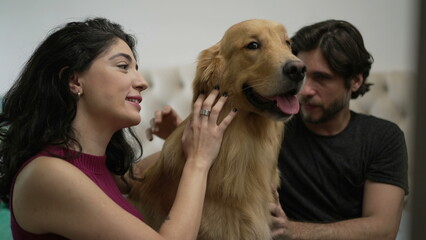 Portrait of a happy couple looking at camera with their Golden Retriever Dog Pet indoors at home