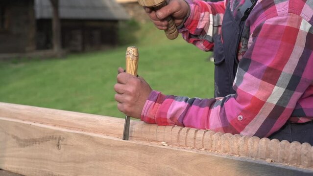 Traditional carving using chisel , hammer and wood log.