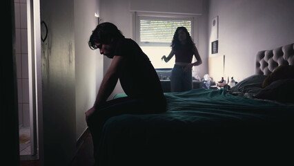 Couple Arguing and Fighting. Man feeling pressure by Female Partner. girlfriend in background discussing relationship while depressed man sits by the bedside feeling frustration
