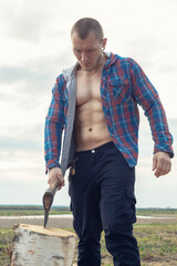 A man stands with an ax. Hack the wood with an acute ax