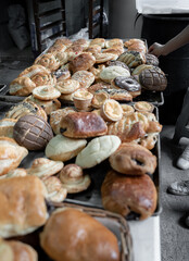 A young Hispanic baker is organizing many different types of Mexican traditional sweet breads