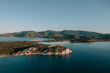 Obraz premium Der Torre di Porto Giunco zum Sonnenaufgang. Turm auf einem Hügel mit türkisblauen Wasser im Norden von Sardinien. Drohnne 3