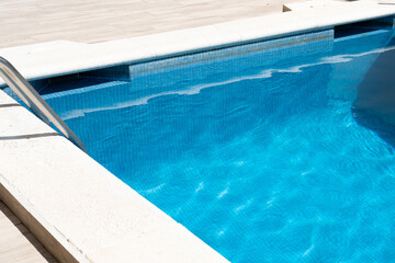 Grab bars ladder in the blue swimming pool