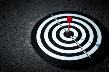 Fototapeta na wymiar The red arrow hits the target in the center of the dartboard on the road. , The concept of setting goals for marketing, investment, and success in work. Achieve objectives, focus on specific points.