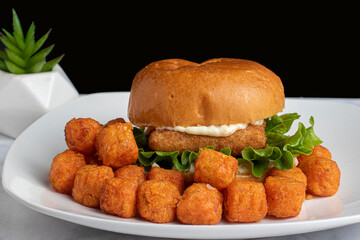 fish sandwich  on a brioxche bun with swet potato tots,