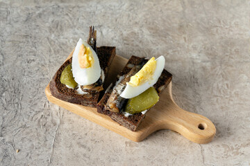 two sandwiches with smoked sardine on a wooden stand, copy space - obrazy, fototapety, plakaty