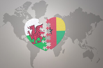 puzzle heart with the national flag of guinea bissau and wales on a world map background.Concept.