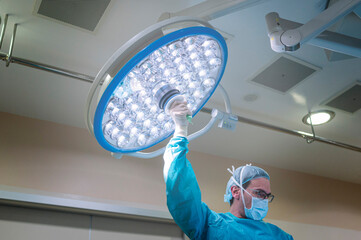 Surgeon's hand moving the lamps in the operating room at the hospital. light bulb health concept