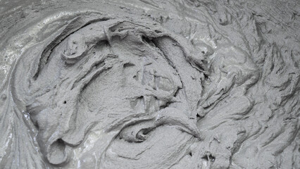 Wet Cement. Gray plastic mass. Mixing of dry building mixes with mixers. Wet mortar mixture for finishing work in construction. Traces of rotation of the tool, prints on cement. Pattern.