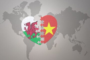puzzle heart with the national flag of vietnam and wales on a world map background.Concept.