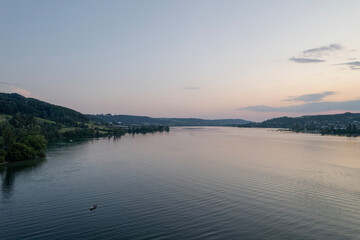 Fototapeta premium aerial footage of sunset over the lake in switzerland and a kayak in the wayer