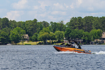 Fototapeta na wymiar Boater on orange wakeboard ski boat enjoying summer day on the lake.