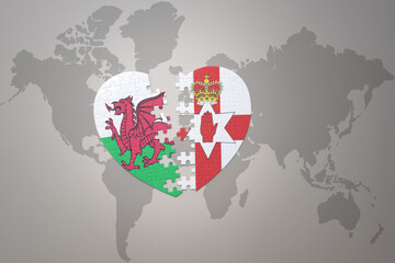 puzzle heart with the national flag of northern ireland and wales on a world map background.Concept.