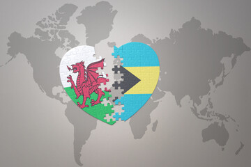 puzzle heart with the national flag of bahamas and wales on a world map background.Concept.