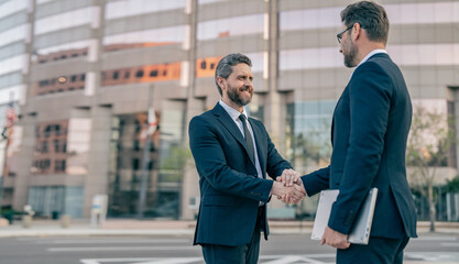two business men handshaking outdoor, copy space banner. two business men in suit are handshaking