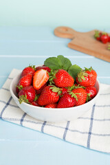 Fresh strawberries in bowl on wooden table