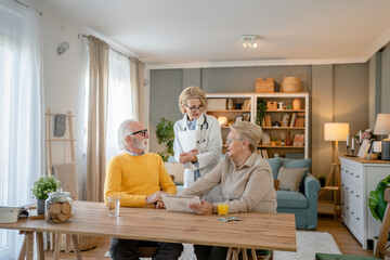 Home visit female doctor with senior man and woman couple at home talk