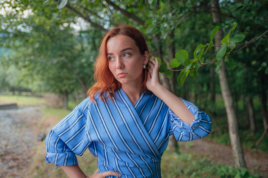 A red-haired girl in a blue suit in nature