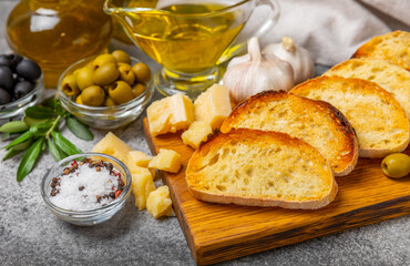 Italian ciabatta bread cut in slices with herbs, olives, pesto sauce, garlic and parmesan cheese on a concrete table. Fresh homemade Italian Ciabatta bread sliced with herbs and spices.Place for text.