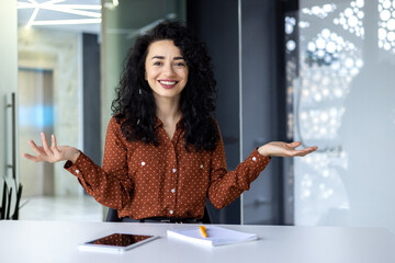 Online customer support video call, Latin American woman looking at web camera smiling and consulting customers, helpline worker working inside office