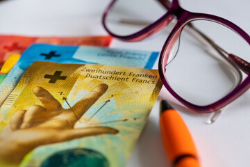 Swiss francs money, women's glasses, white sheet of paper, pen, concept, bill payments,...