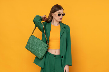 Fashionable female model in oversized green suit on isolated yellow background.