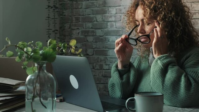 One adult woman touching her head for headache migraine after work on computer at the table. Concept of tired and stress people with problems and painful health bad condition working on laptop online