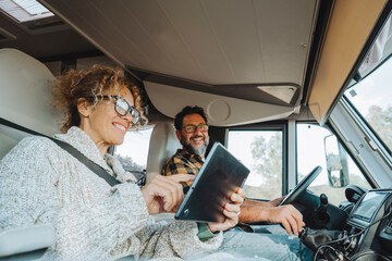 Happy couple of tourist traveler enjoy drive and live in camper van and using laptop to manage the...