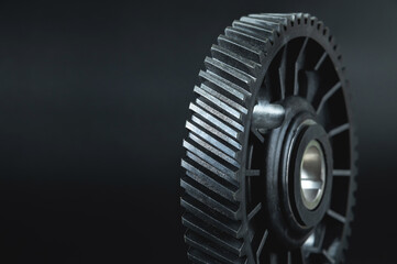 Black timing gear of an internal combustion engine on a black background