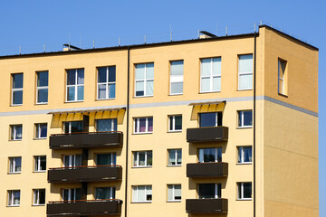 Renovated and insulated multistorey apartment building facade fragment against a blue sky background