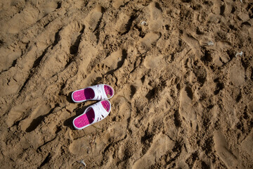 Chanclas abandonadas en la fina arena de una de las playas del Mar Mediterráneo mientras su dueño está en el agua disfrutando de la buena temperatura veraniega.